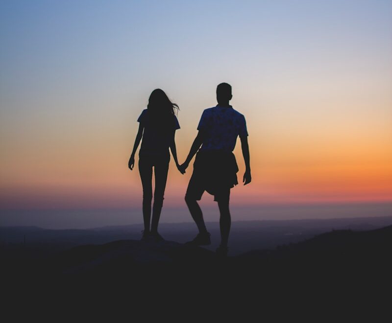 man and woman holding hands in silhouette photography